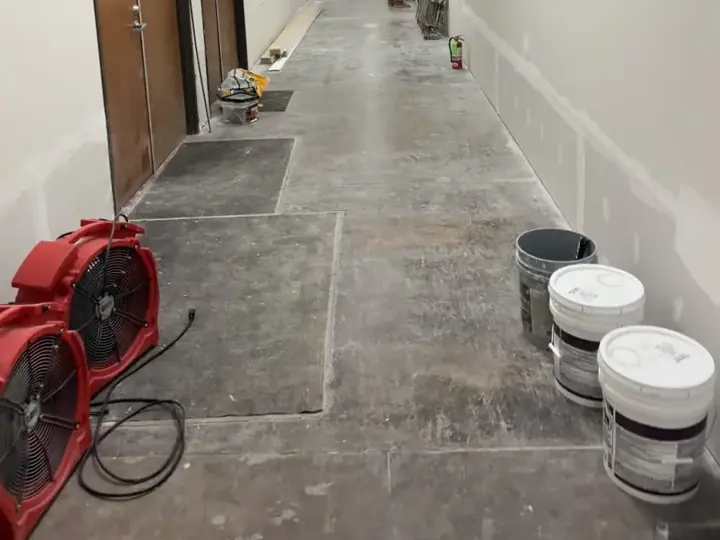 Air movers drying a hallway slab after flooring removal