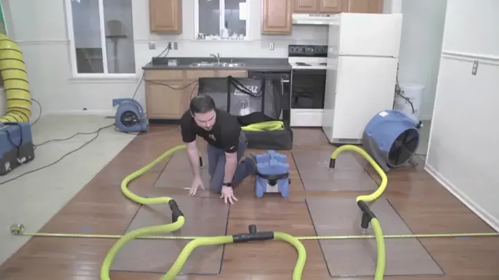 Technician setting hardwood floor drying mats in a Weatherford kitchen