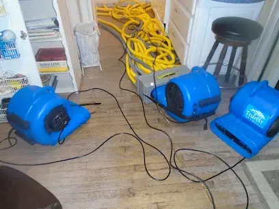 Air movers and hoses drying a wet floor during a Weatherford water damage dry-out