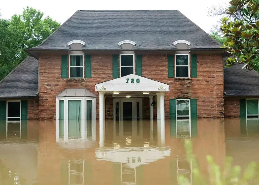 Brick home standing in brown flood water after a flash flood