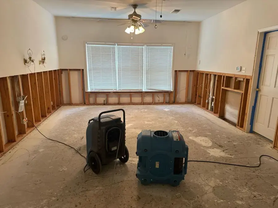 Dehumidifier and air mover drying a room with flood-cut drywall