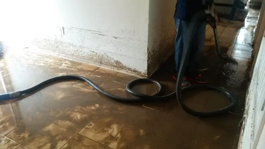 Extraction hose pulling standing water off a flooded tile floor in a Weatherford home